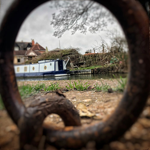 A narrowboat, seen through a mooring ring in the foreground